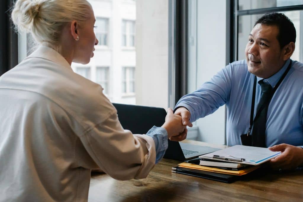 Article CIP-KYC - Un agent de banque serre la main d’une cliente à son bureau