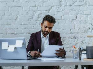 Article compte bancaire en agence ou en ligne - Un entrepreneur consulte un document relatif à l’ouverture d’un compte bancaire