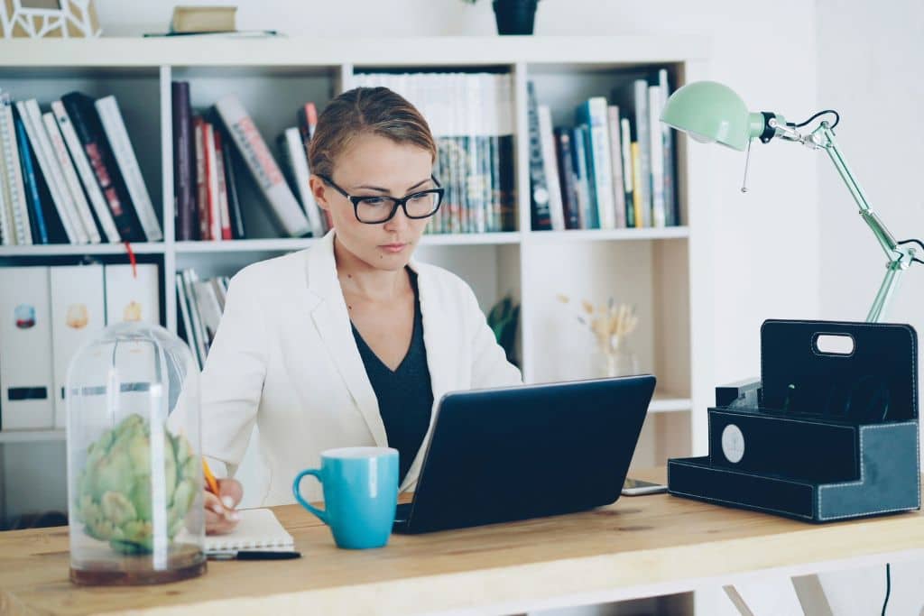 Article compte bancaire en agence ou en ligne - Une entrepreneure consulte son ordinateur pour suivre l’ouverture de son compte bancaire professionnel