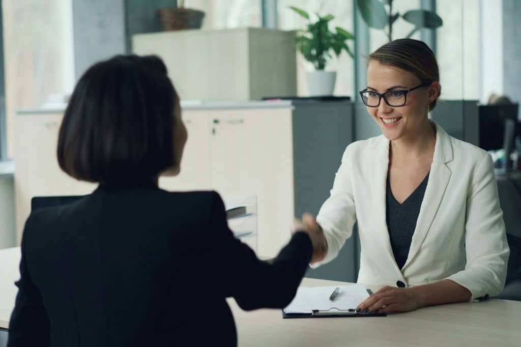 Article compte bancaire en agence ou en ligne - Une responsable d’agence bancaire serre la main d’une cliente