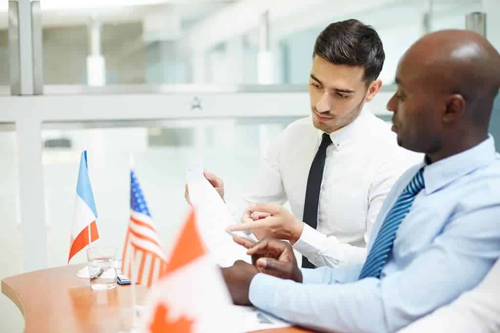 Article création d'entreprise aux États-Unis pour non-résidents - Deux hommes d'affaires, français et américain, vérifiant un dossier administratif.