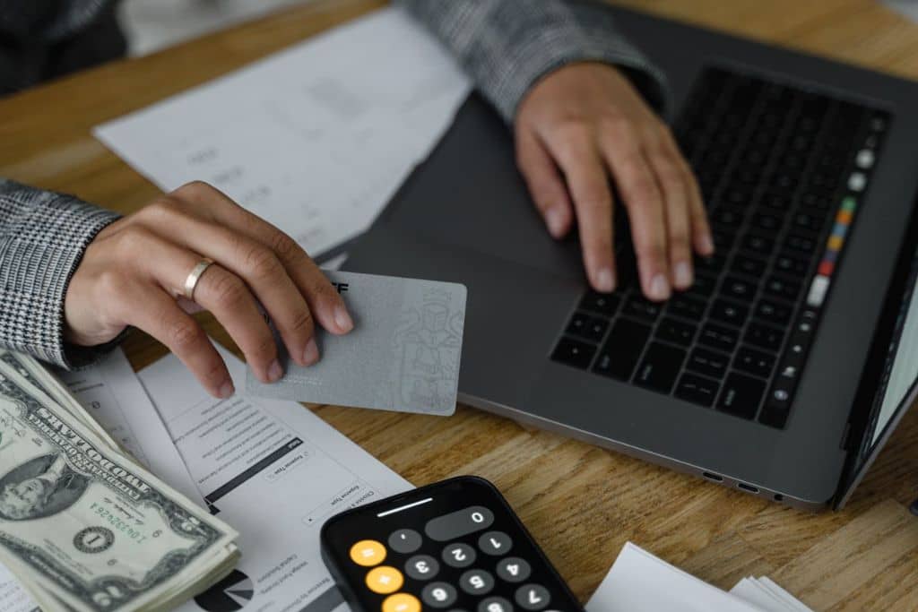 Article Créer une LLC en Alaska - Dossiers de paiement, une main qui tend une carte de crédit et des dollars US