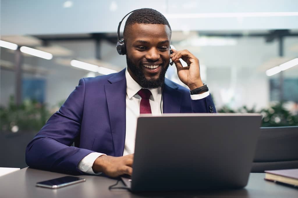 Un représentant légal avec casque, au téléphone et sur ordinateur, aidant un client à créer une LLC en Arizona.