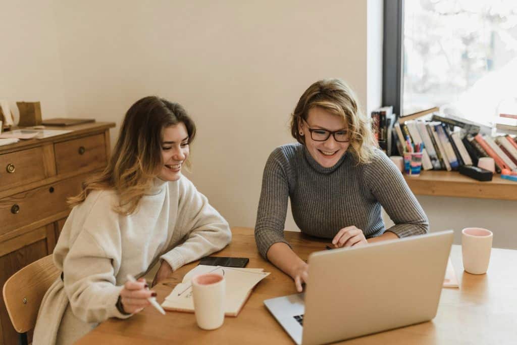 Article Créer une LLC au Dakota du Sud - Deux entrepreneures souriantes visualisant des informations sur un ordinateur portable