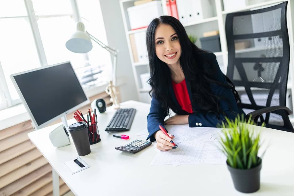 Article creer une LLC à Hawaii - Une comptable souriante assise sur son bureau