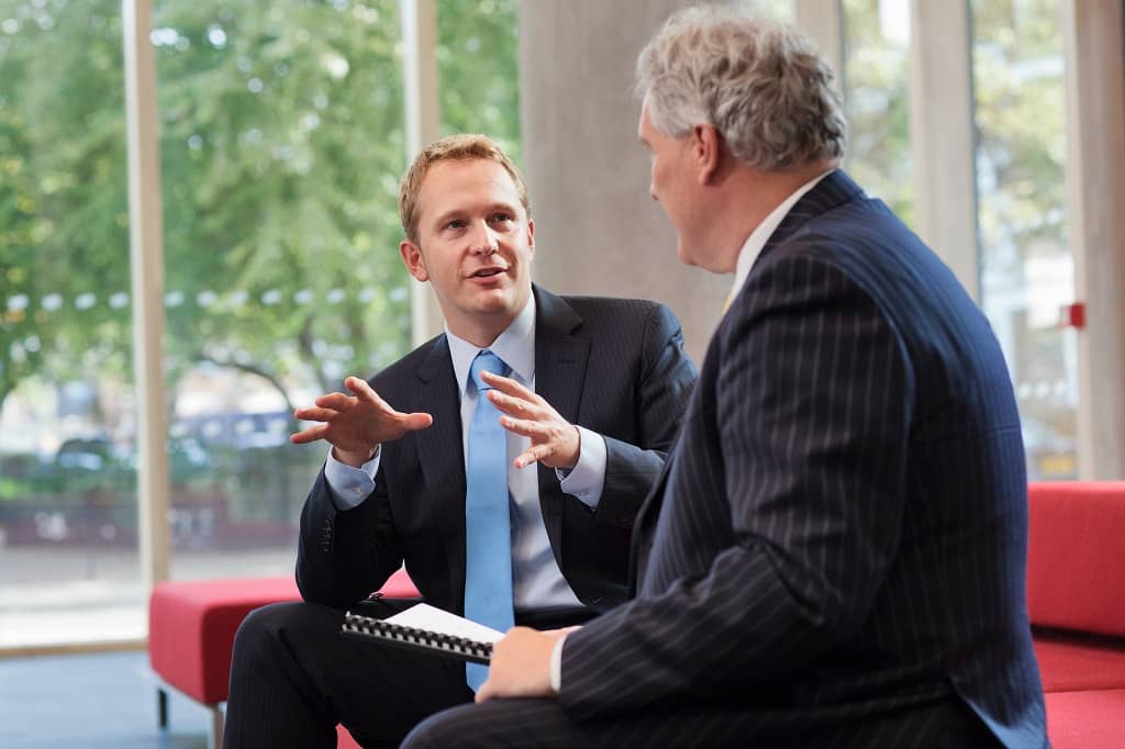 Article créer une LLC dans l'Idaho - Deux hommes comptables assis sur un canapé rouge échangeant une discussion