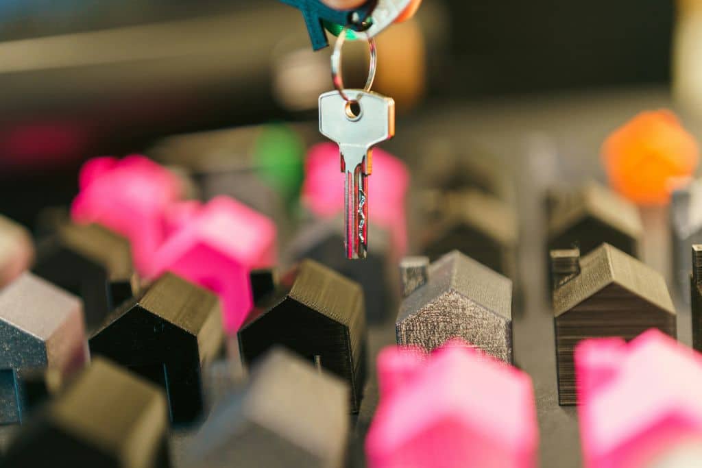 Article créer une llc dans le Michigan - Une clé tenue par une main au-dessus de petites maquettes de maison