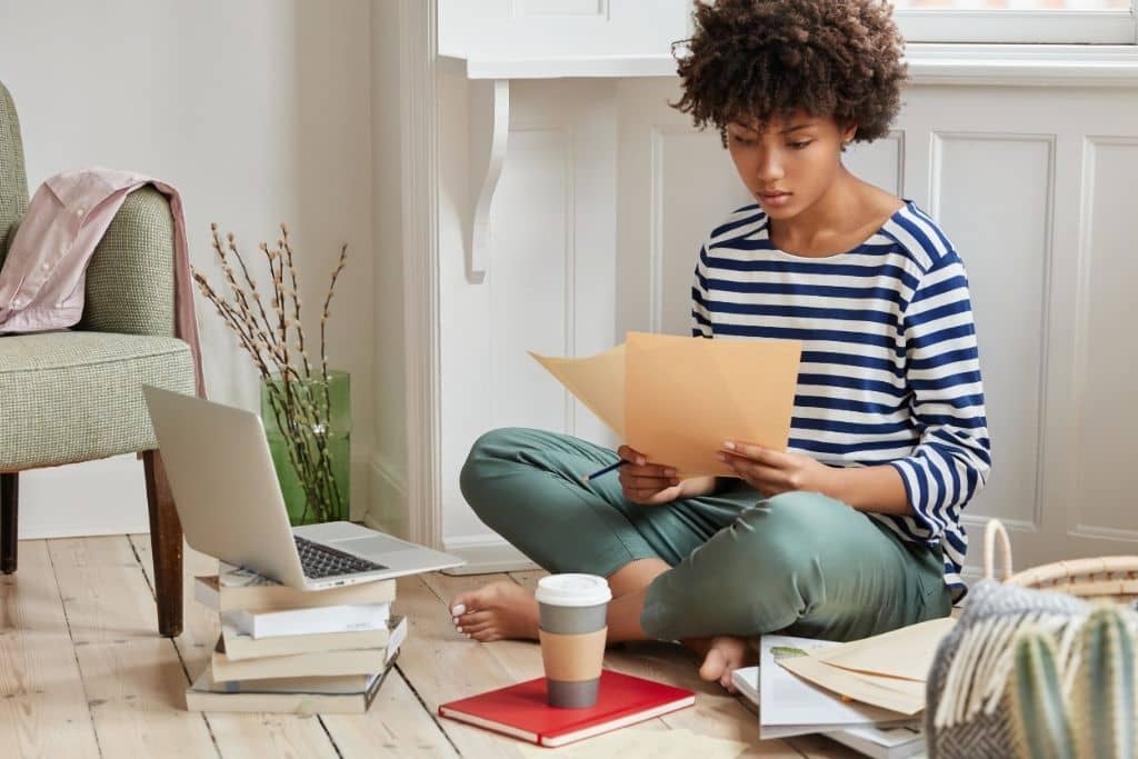 Article créer une llc dans le Missouri - Une entrepreneure étudiant des dossiers assise par terre avec son ordinateur