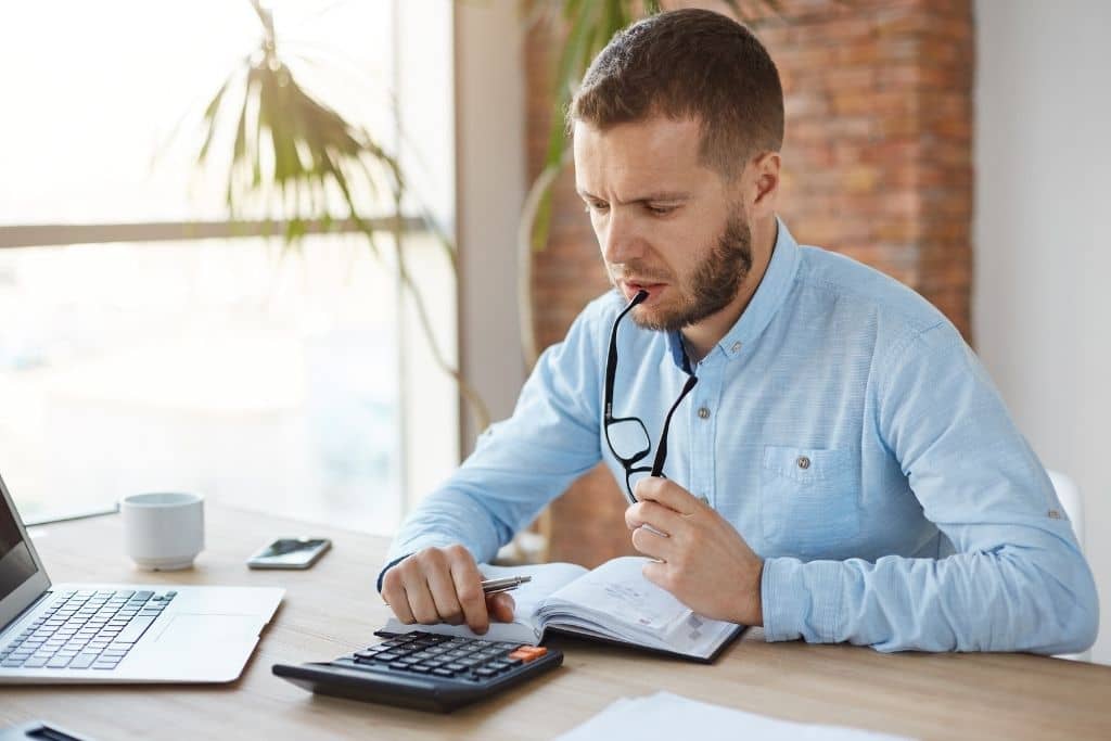 Article créer une llc dans le Missouri - Un homme effectuant des calcules avec une machine à calculer sur son bureau