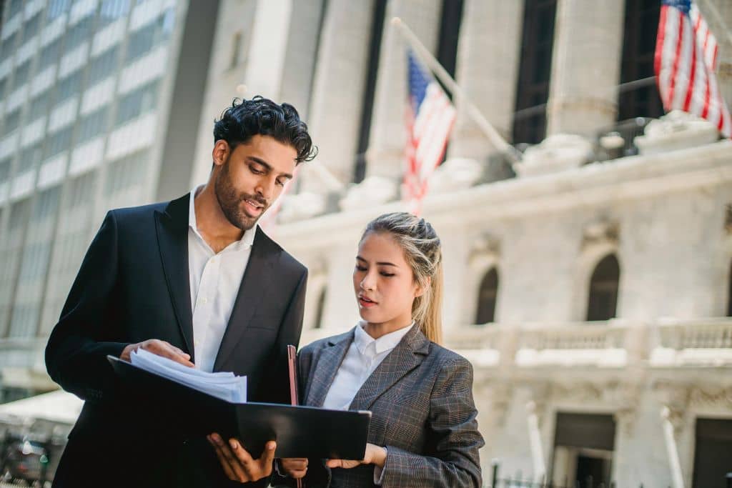 Article créer une llc à New York - Deux collègues qui vérifient des documents ensemble en extérieur