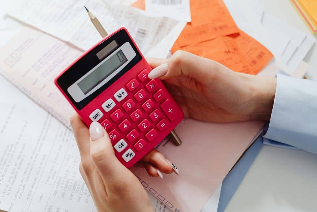 Article créer une llc dans le Nouveau-mexique - Les mains d'une femme en train de calculer les impôts avec une machine à calculer