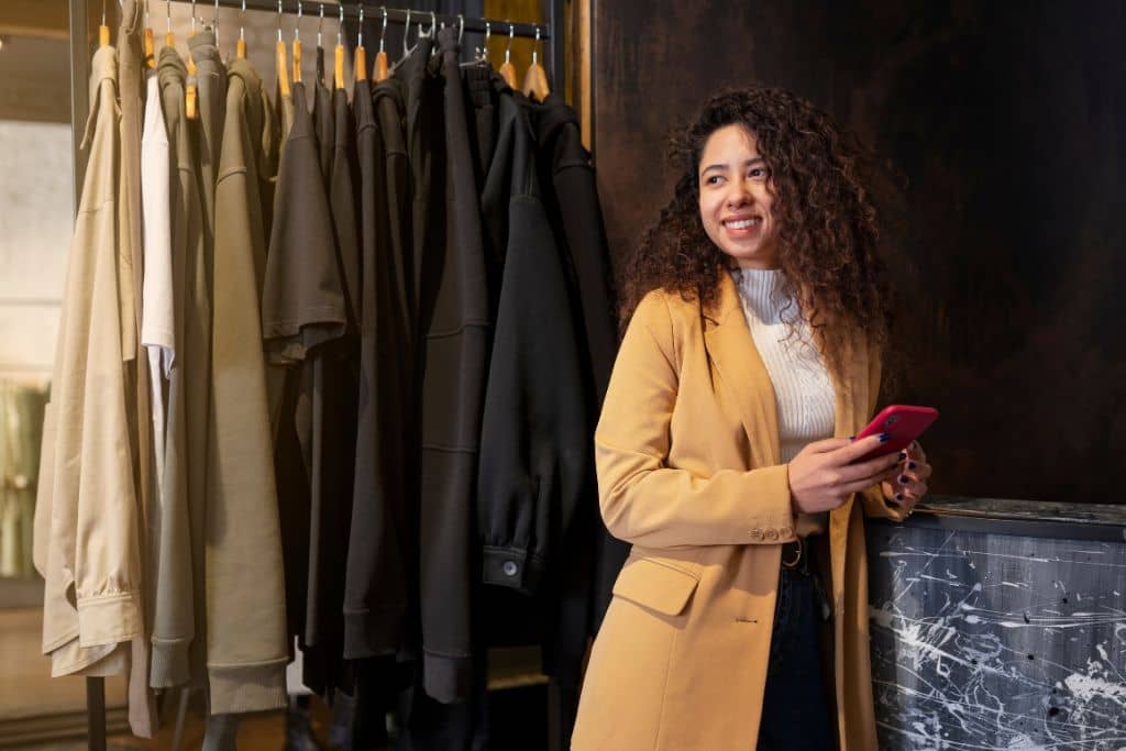 Article créer une llc dans le Rhode Island - Une entrepreneure souriante dans sa boutique tenant un smartphone