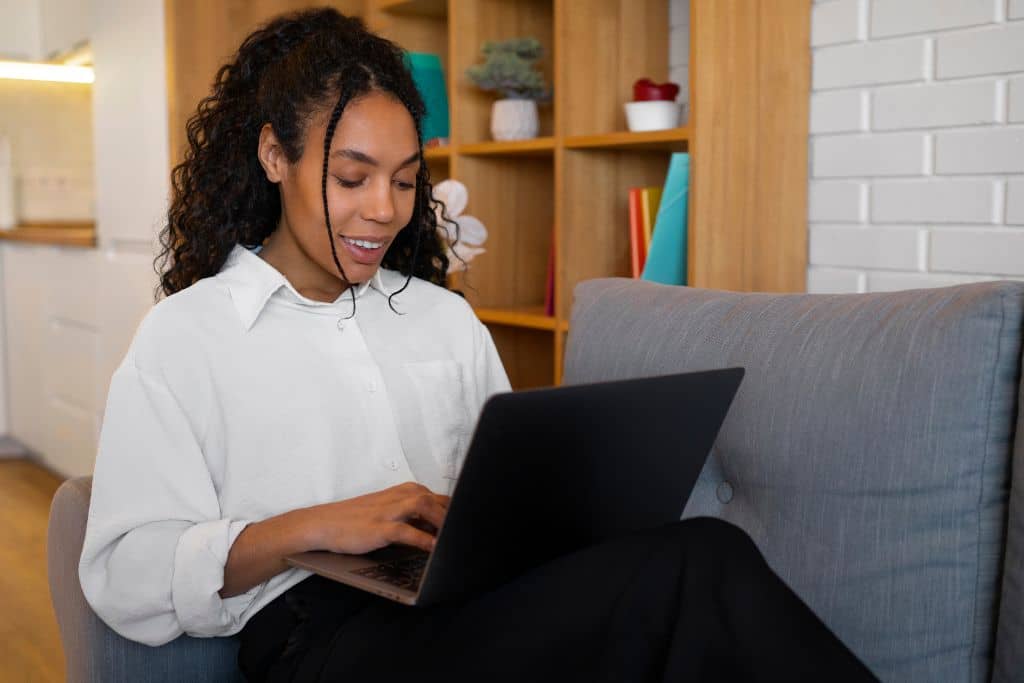 Article créer une llc à Washington - Une jeune femme entrepreneure travaillant sur son ordinateur assise sur un sofa