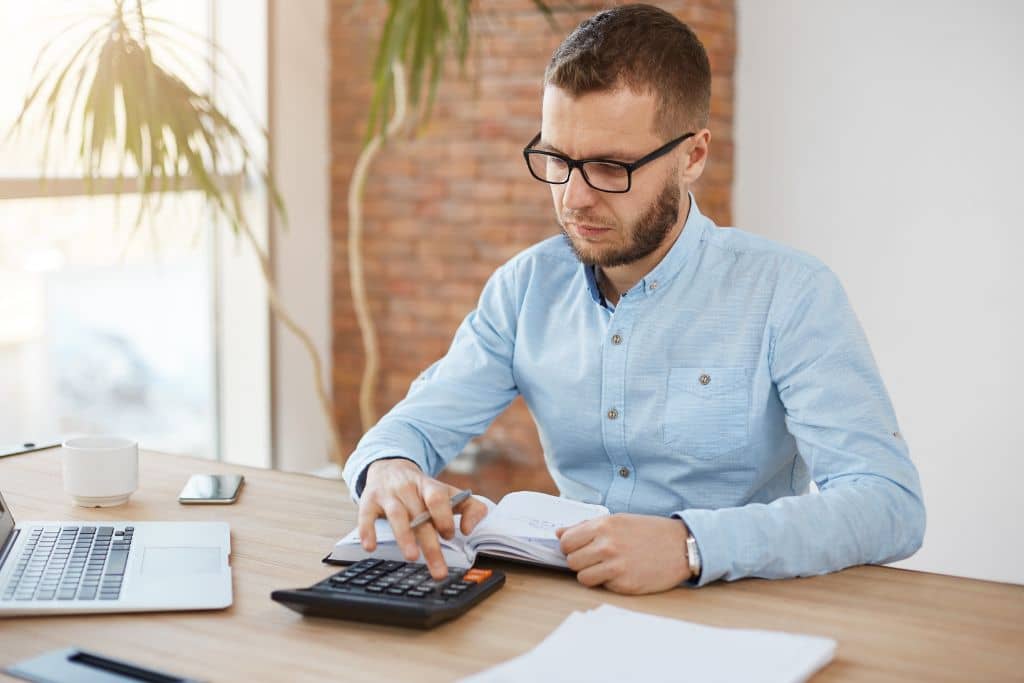 LLC vs C-Corp du Delaware - Un entrepreneur concentré calculant les coûts de son projet entrepreneurial