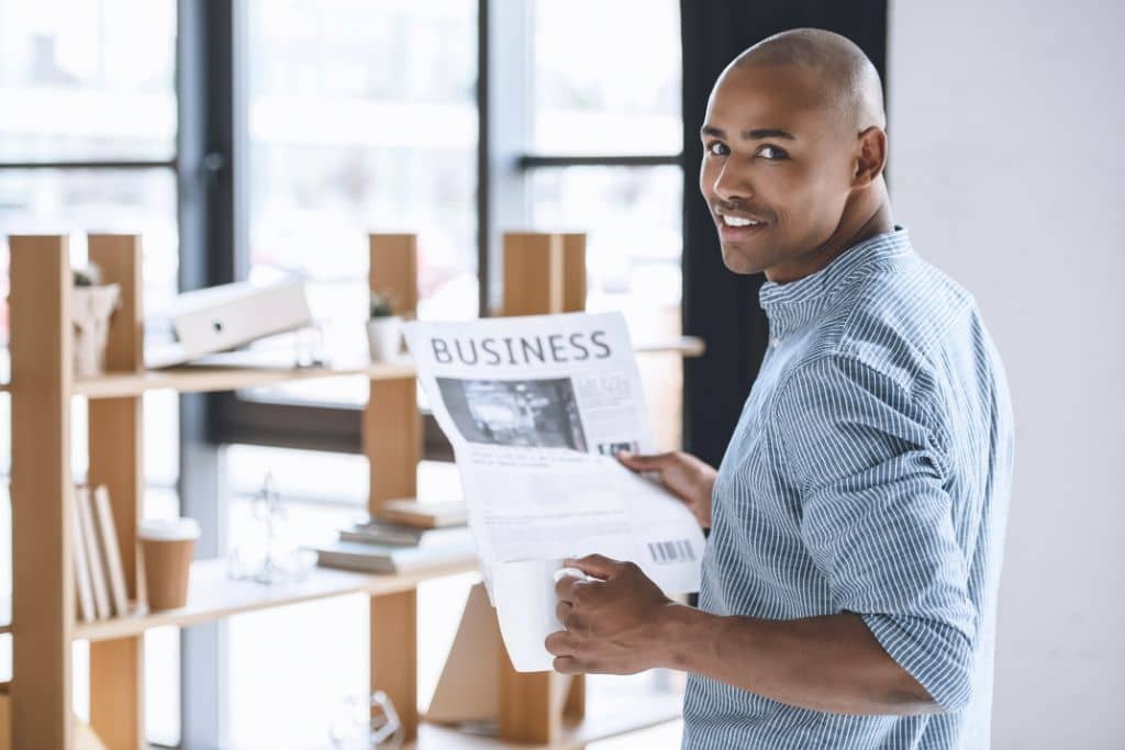 Article LLC vs Limited Company d’Irlande - Un entrepreneur tenant un journal dans une main et un café dans l'autre