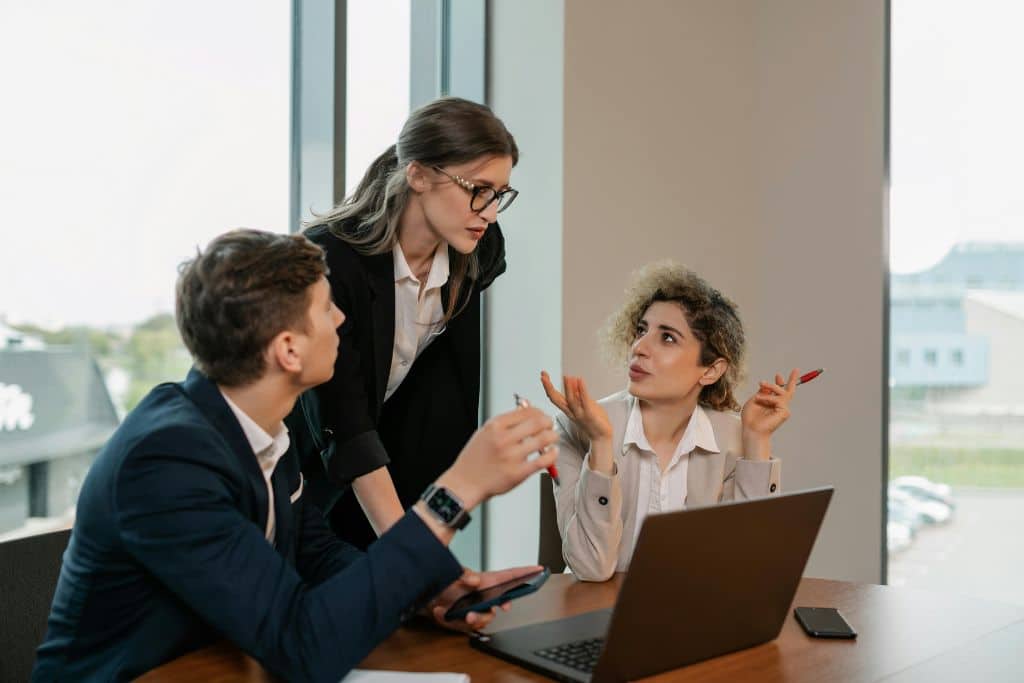 Article LLC vs Private Limited Company du Royaume-Uni - Une équipe de trois collègues échangeant des idées et planifiant un projet professionnel