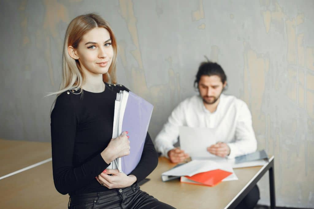 Article LLC vs Private Limited Company de Singapour - Une entrepreneure tenant des documents en main, avec un collègue en arrière-plan 