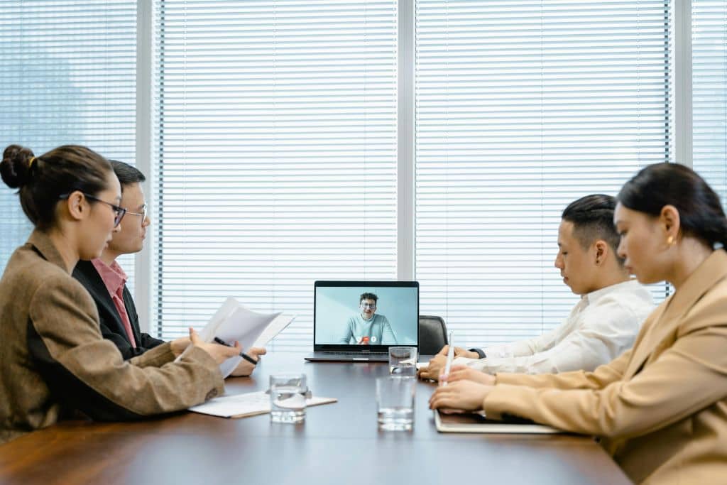 Article LLC vs Private Limited Company de Singapour - Une équipe en réunion autour d’une table, participant à une visioconférence avec leur dirigeant