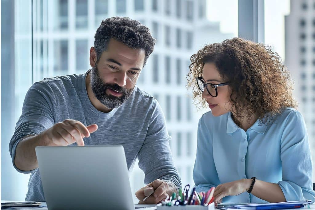 Article LLC vs Société holding maltaise - Un homme et une femme, associés, échangeant des idées et analysant des informations affichées à l’écran d'un ordinateur
