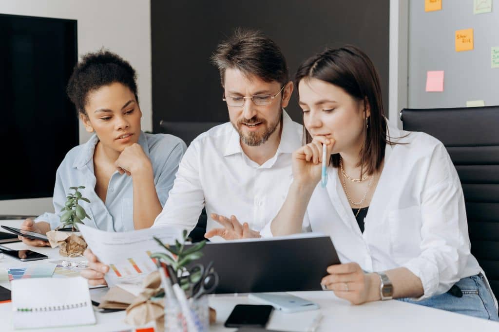 Article LLC vs Société holding maltaise - Trois collaborateurs examinent ensemble un rapport d’entreprise
