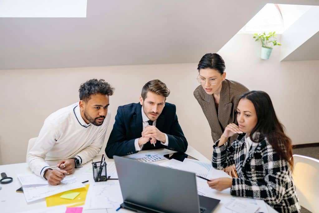 Article LLC vs Société holding maltaise - Une équipe de quatre personnes examine des données d'entreprises sur un ordinateur