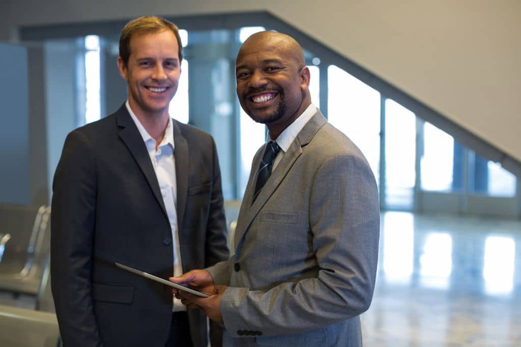 LLC vs Stiftung du Liechtenstein - Deux entrepreneurs debout, souriants et confiants, dans un cadre professionnel