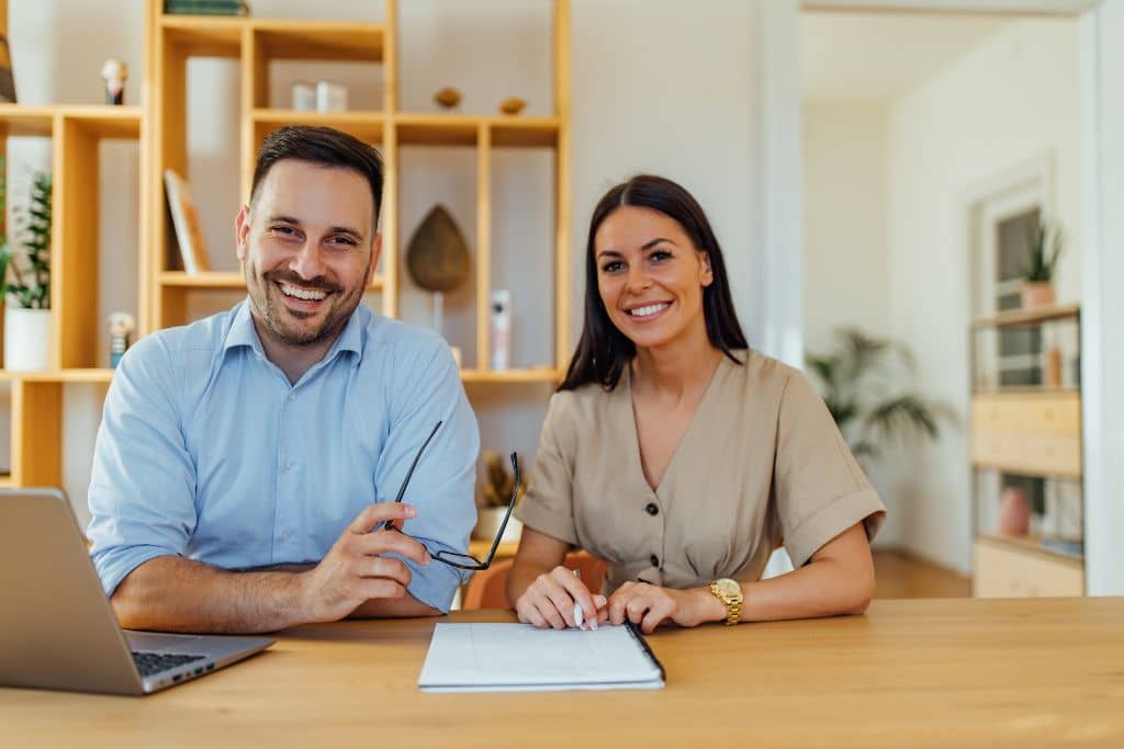 LLC vs Stiftung du Liechtenstein - Un couple d’entrepreneurs souriants, assis chez eux, préparant leur projet