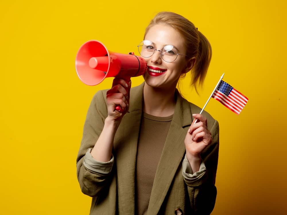 Marketing aux États-Unis pour les entrepreneurs non-résidents - Une femme avec un mégaphone à la main et un petit drapeau US