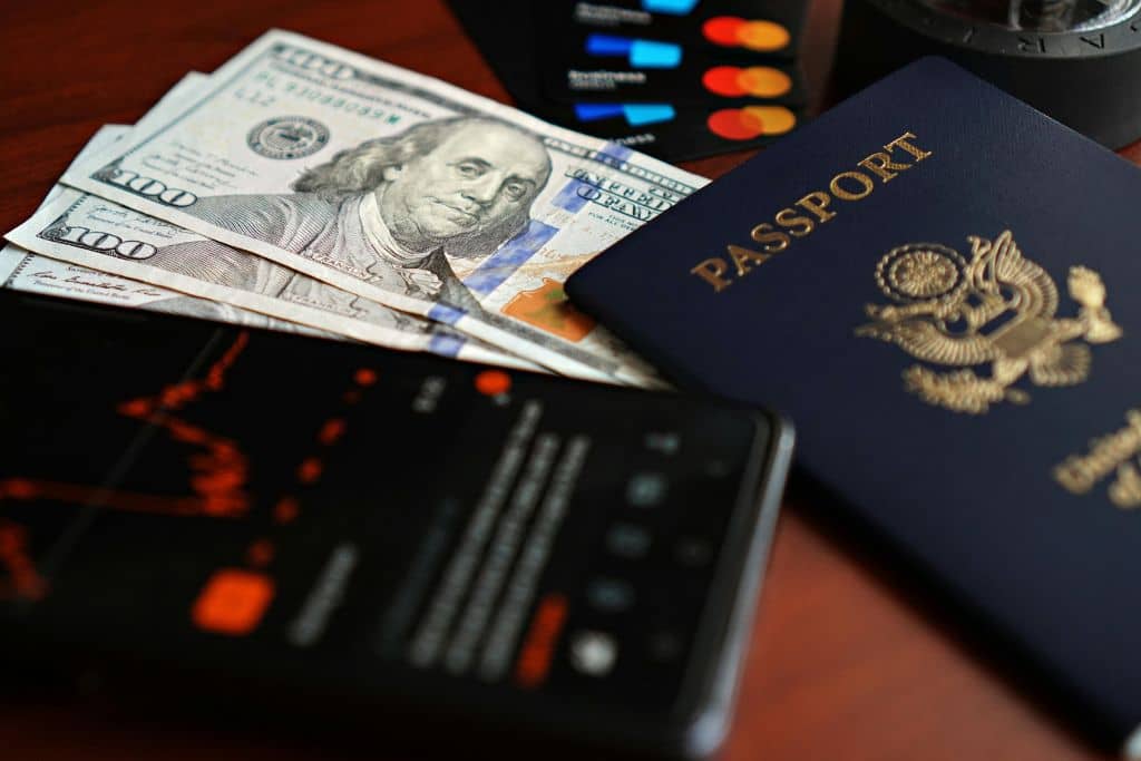 Article pièces à fournir aux banques US - Un passeport, des dollars américains et un smartphone posés sur une table