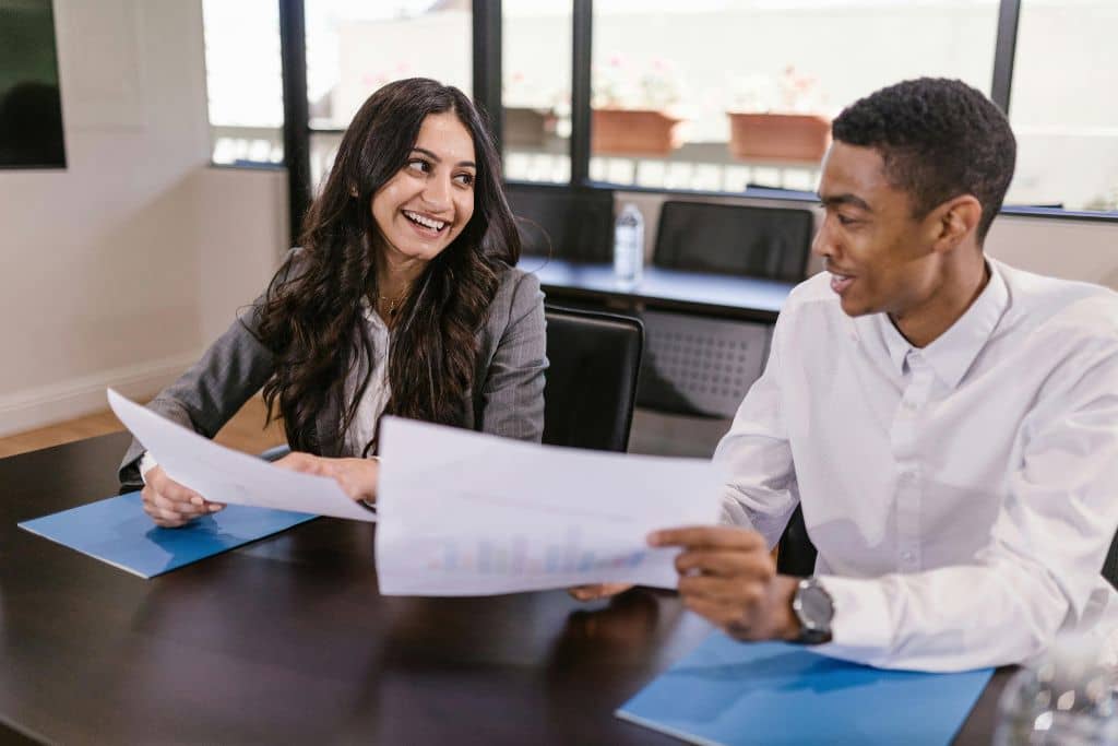 Article pièces à fournir aux banques US - Deux collègues se sourient en tenant des documents