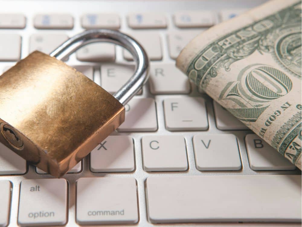 Article sécurité, fraudes et limites de risque - Un cadenas et un paquet de dollars us au-dessus d'un clavier d'ordinateur