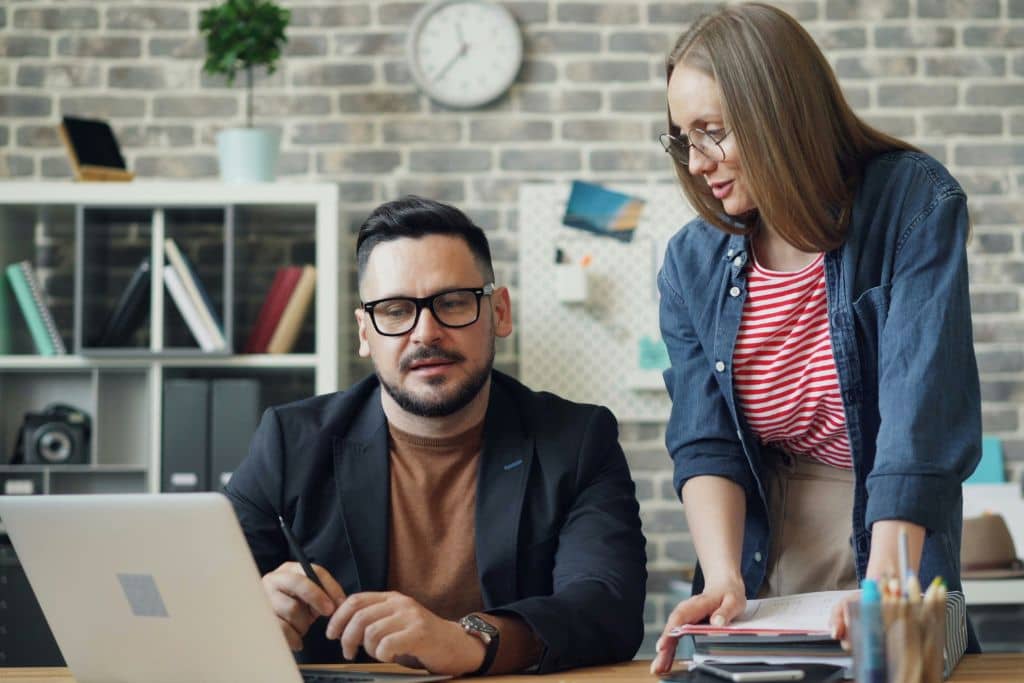 Article sécurité, fraudes et limites de risque - Un entrepreneur et sa collègue échangent des conseils devant un ordinateur